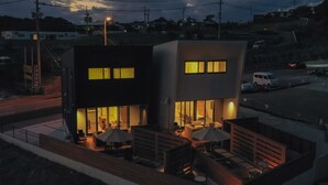 Un edificio moderno dividido en dos secciones, cada una con un balcón que ofrece asientos y mesas al aire libre.