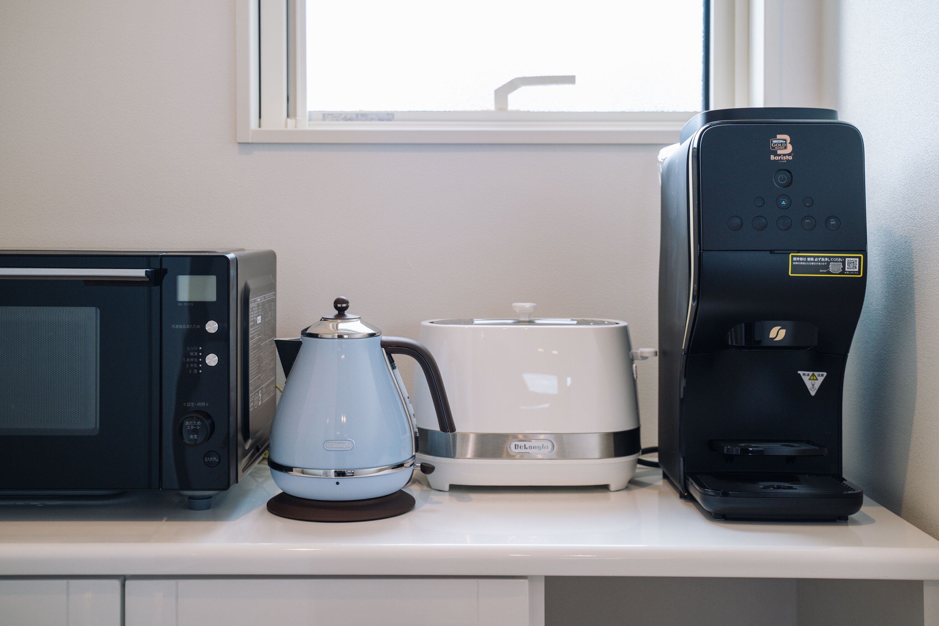 A kitchen counter with a microwave, a coffee maker, and a toaster.