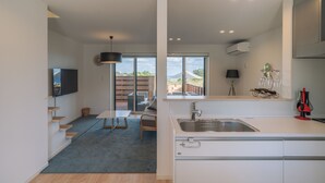 Una cocina moderna con un amplio ventanal, un comedor con mesa y sillas, y una escalera que lleva a un nivel superior.