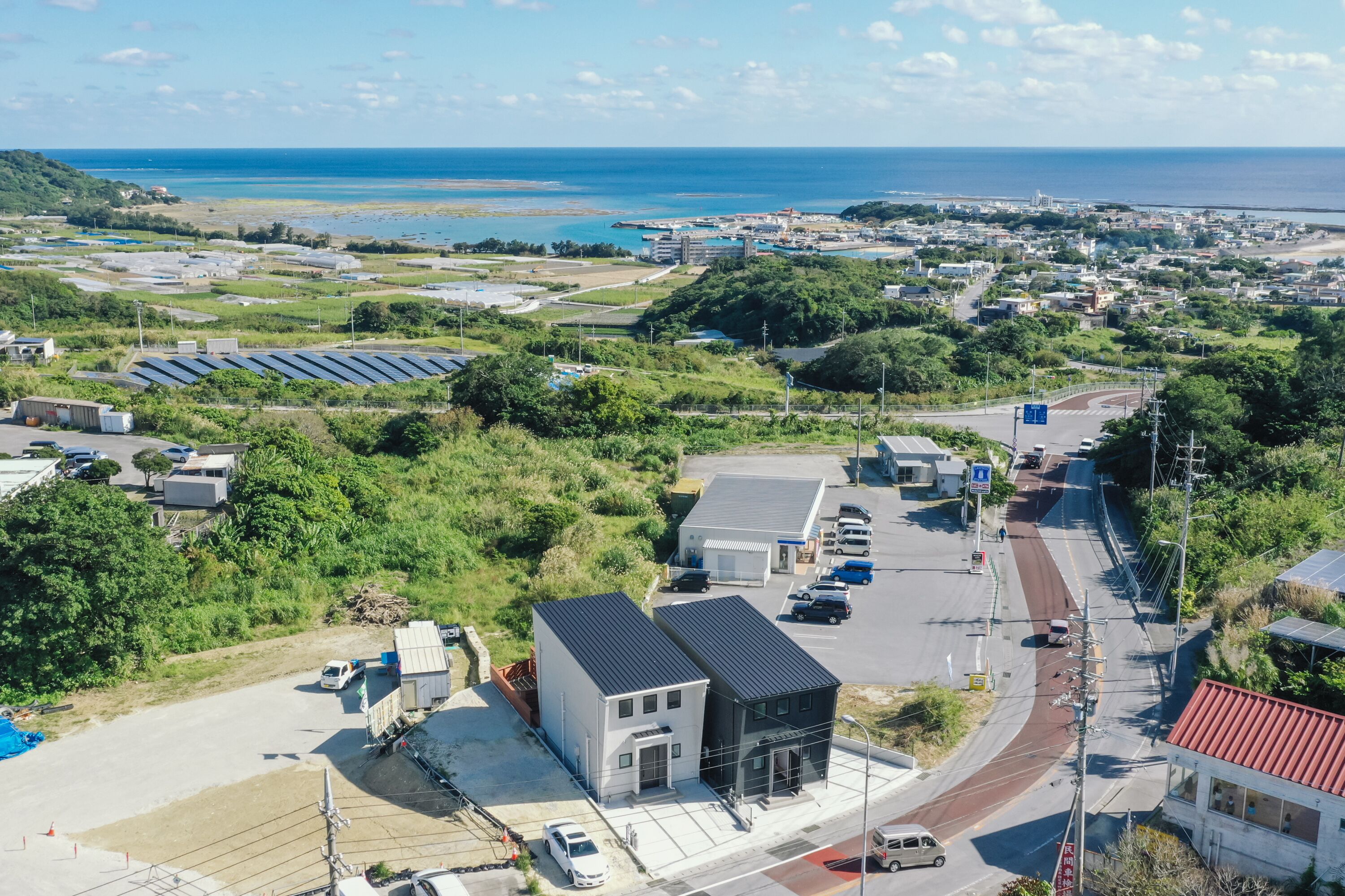 A coastal town with a main road, parked cars, and a building with solar panels.