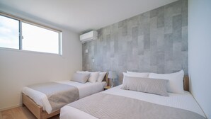 Una habitación de hotel moderna con dos camas, un ventanal grande y una pared con textura.