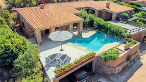 Une villa avec piscine, un espace extérieur aménagé et un garage.