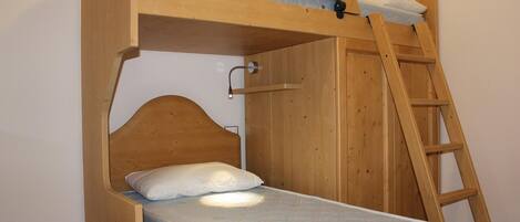 A bunk bed with a ladder, a mattress, and a pillow.