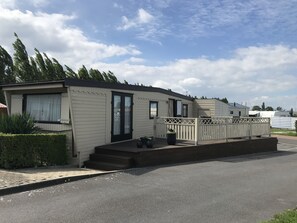 Une maison mobile dotée d’un porche à l’avant, d’une petite terrasse et d’un espace clôturé.