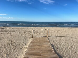 Une promenade en bois menant à la plage, avec des empreintes de pas dans le sable.