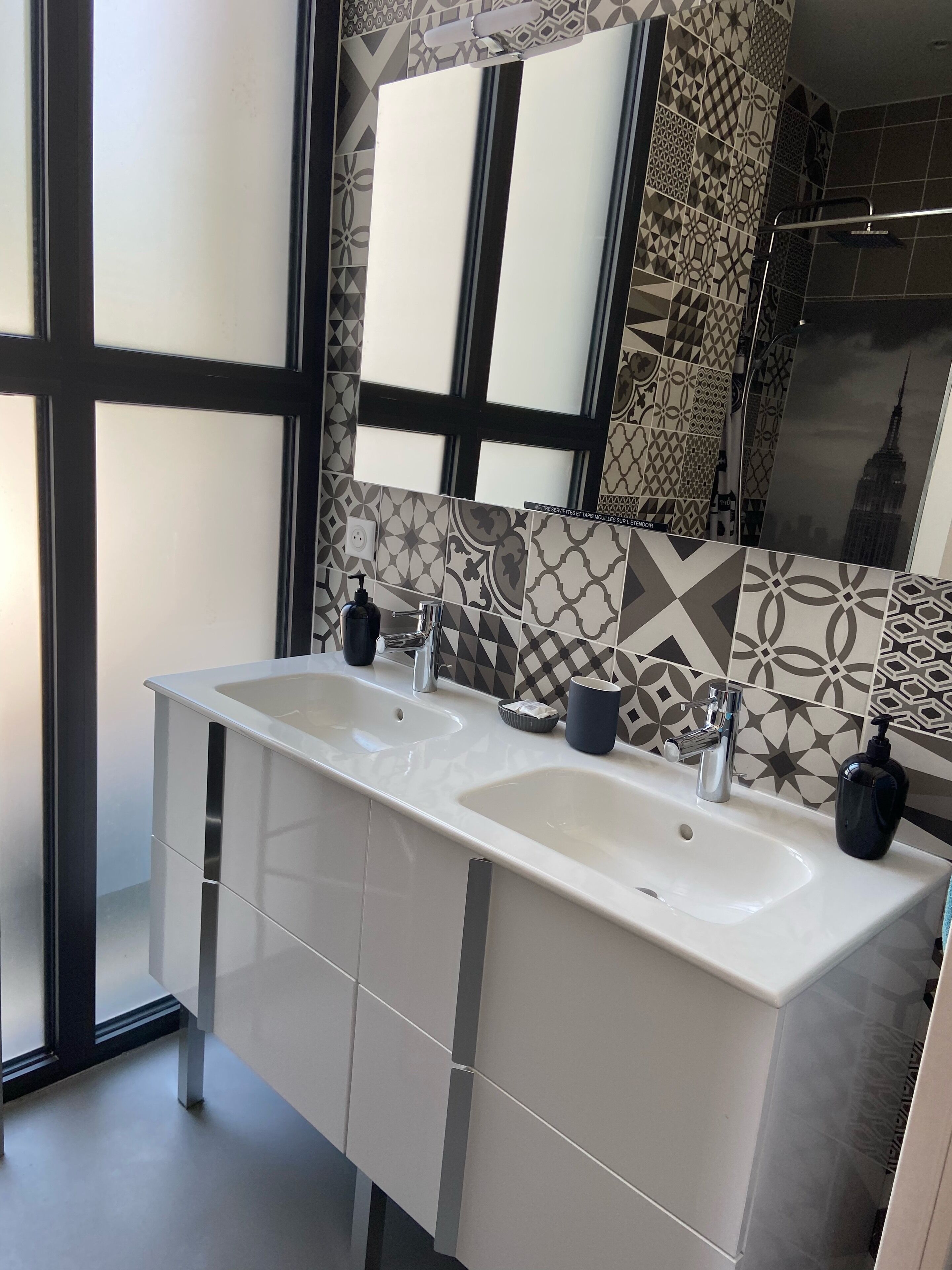 Een moderne badkamer met twee wasbakken, een grote spiegel en tegelwerk met een patroon.