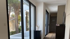 A hallway with wooden flooring, large sliding glass doors, and a view of a swimming pool.