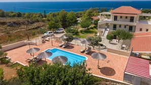Un resort con piscina, tumbonas, sombrillas y vistas al mar.