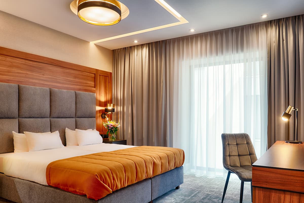 Ein modernes Hotelzimmer mit einem großen Bett, einem Schreibtisch und einem Stuhl.