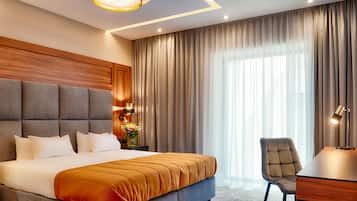 A modern hotel room with a large bed, a desk, and a chair.