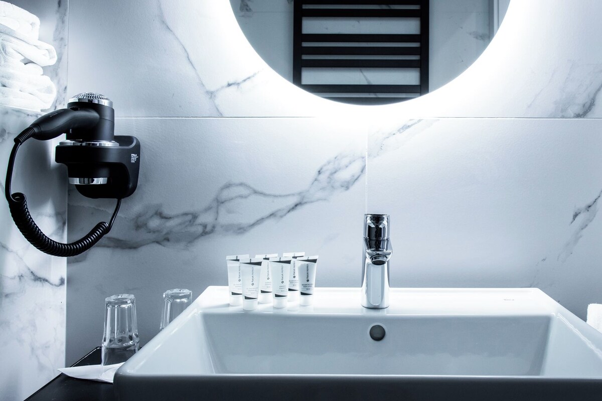 A bathroom with a white sink, a black hairdryer, and a mirror.