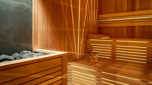 Sauna, jossa on puiset lauteet ja kiviseinä.