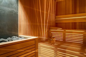 Un sauna avec des bancs en bois et un mur en pierre.