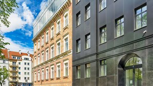 Monikerroksinen rakennus, jossa yhdistyvät moderni ja perinteinen arkkitehtuuri. Siinä on suuret ikkunat ja huomiota herättävä kaareva sisäänkäynti.