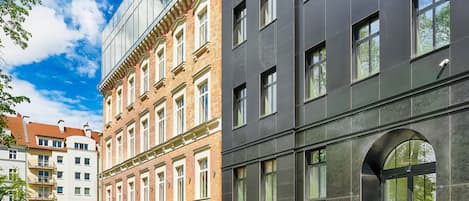 Un edificio de varios pisos con una mezcla de arquitectura moderna y tradicional, que presenta grandes ventanales y una entrada en arco destacada.