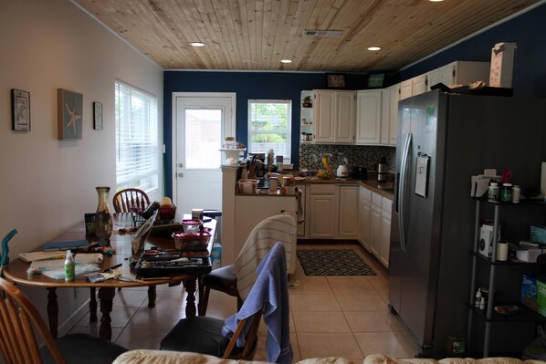 Una cocina con armarios de madera, un refrigerador y una mesa de comedor con sillas.