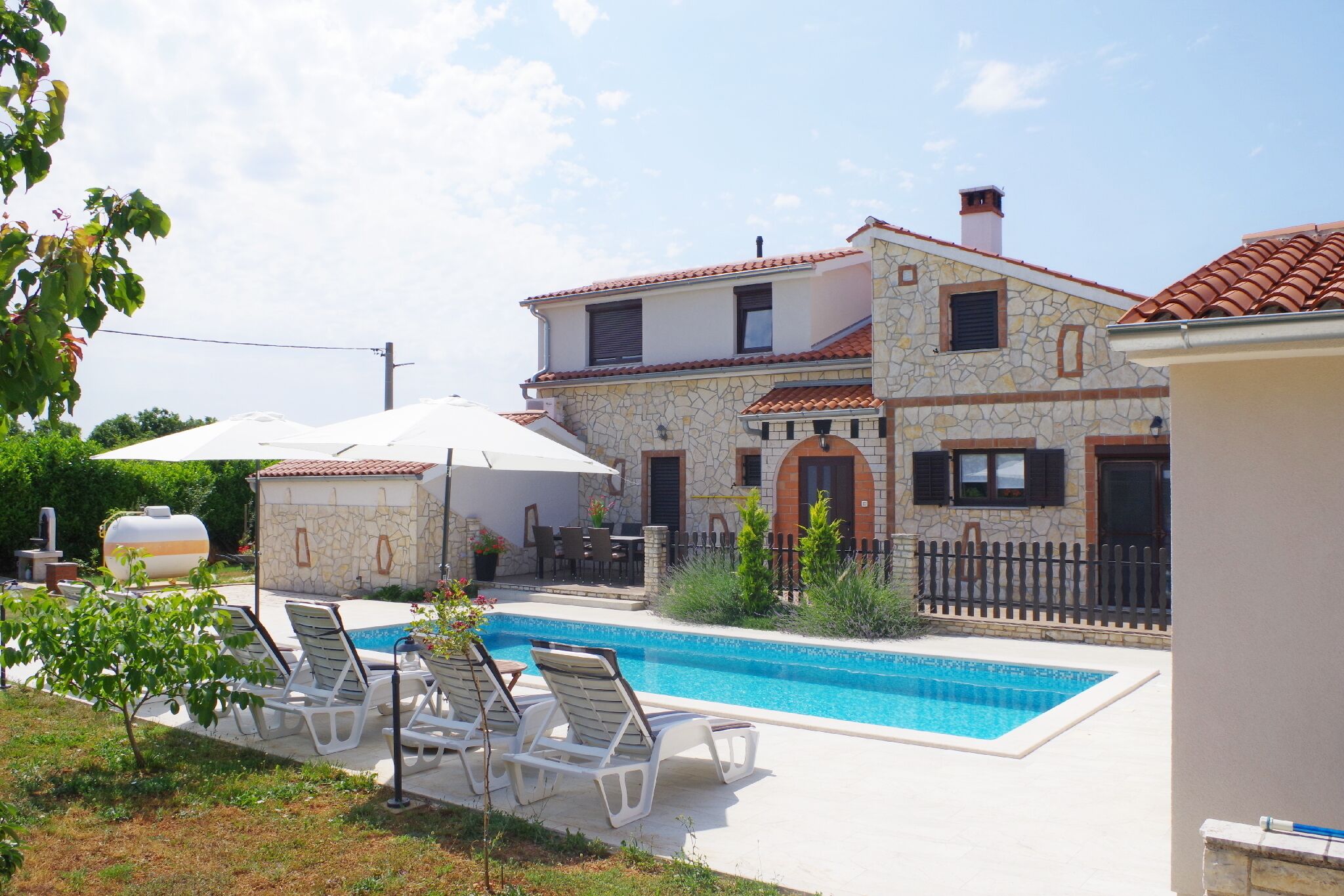 Une maison à deux étages avec une piscine, du mobilier d’extérieur et un jardin clos.