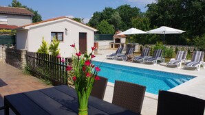 Ein Poolbereich mit Liegestühlen, einem Tisch und einer Blumenkomposition.