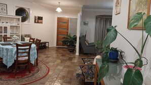 Un comedor con una mesa dispuesta para dos, un sofá y una planta en maceta.