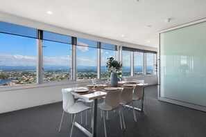 A modern office space with a panoramic view of a cityscape through large windows. - Luxury 3 Bedroom Apartment with Ocean Views (Surfers Paradise)