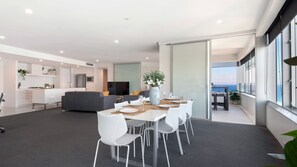 A modern living space with a dining area, kitchen, and a balcony with a view.