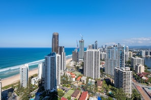 Un paysage urbain côtier avec de hauts immeubles, une plage et un ciel dégagé.
