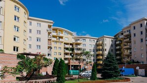 A multi-story residential building with balconies, a parking area, and a landscaped garden. - ShortStayPoland Św. Wincentego B7 (Warsaw)