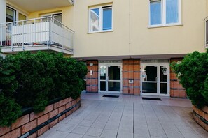 A building with two entrances, each marked with a sign indicating room numbers. There is a small balcony with a metal railing on the left side. - ShortStayPoland Św. Wincentego B7 (Warsaw)