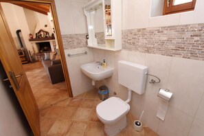 A compact bathroom with a toilet, sink, and mirror. - Holiday House San Pruti (Rovinj)
