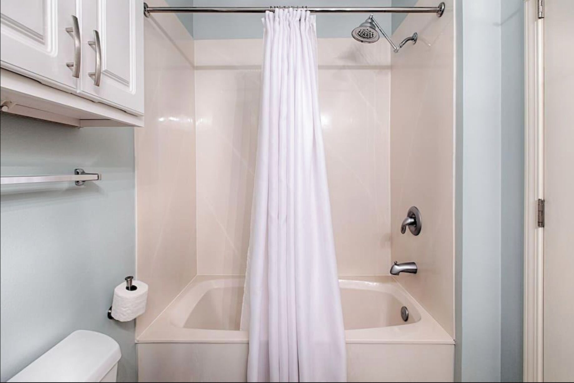Ein Badezimmer mit einer Badewanne, einer Duschvorhang, einer Toilette und einem Handtuchhalter.