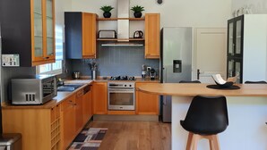 Moderni keittiö, jossa on puukalusteet, sisäänrakennettu uuni, mikroaaltouuni ja jääkaappi.