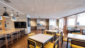 Un restaurante moderno con varias mesas y sillas, un televisor y una zona de cocina.