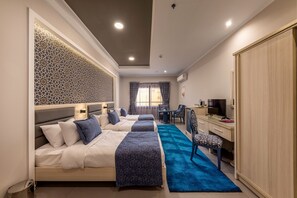 Relax in a stylish room with a large bed, desk, and wardrobe, surrounded by geometric patterns and sheer curtains.