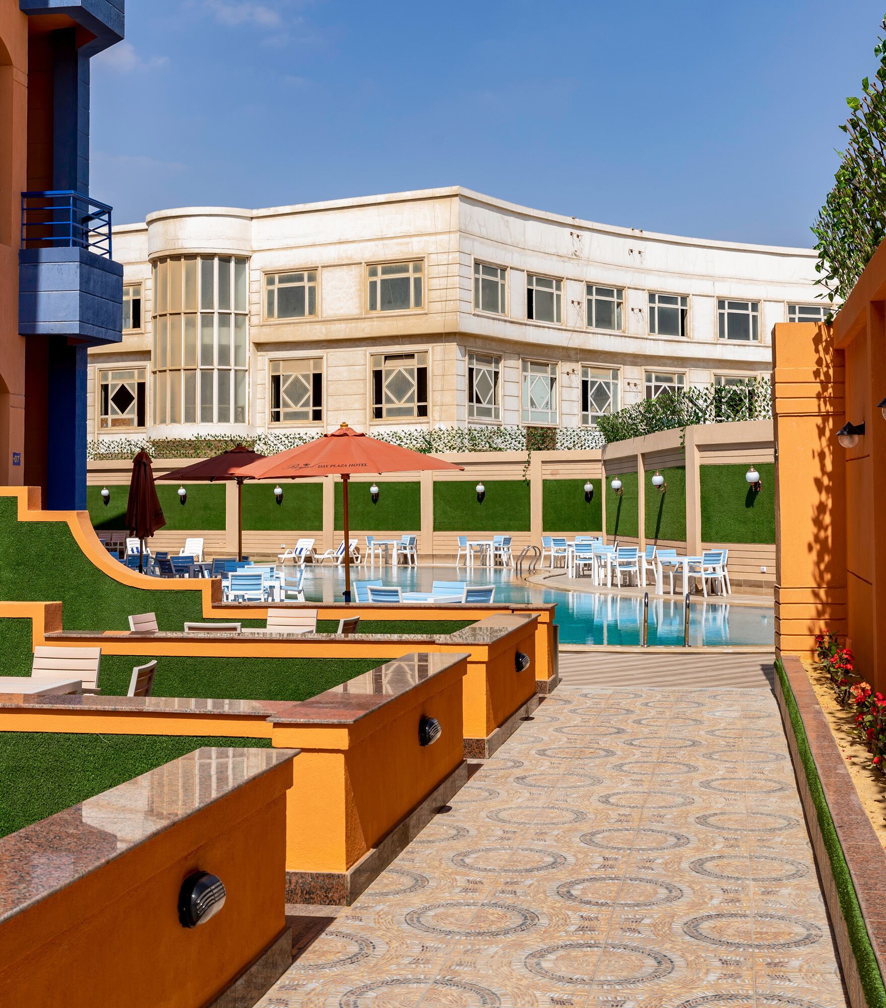 A hotel with a pool, lounge chairs, and a building with large windows.