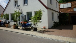 A two-story building with a white facade and a red roof. There is a sign on the building indicating it is a restaurant. - Gasthaus - Pension Am Buchberg (Mönchsdeggingen)