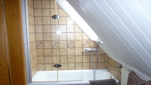 A bathroom with a bathtub, shower, and tiled walls. - Gasthaus - Pension Am Buchberg (Mönchsdeggingen)