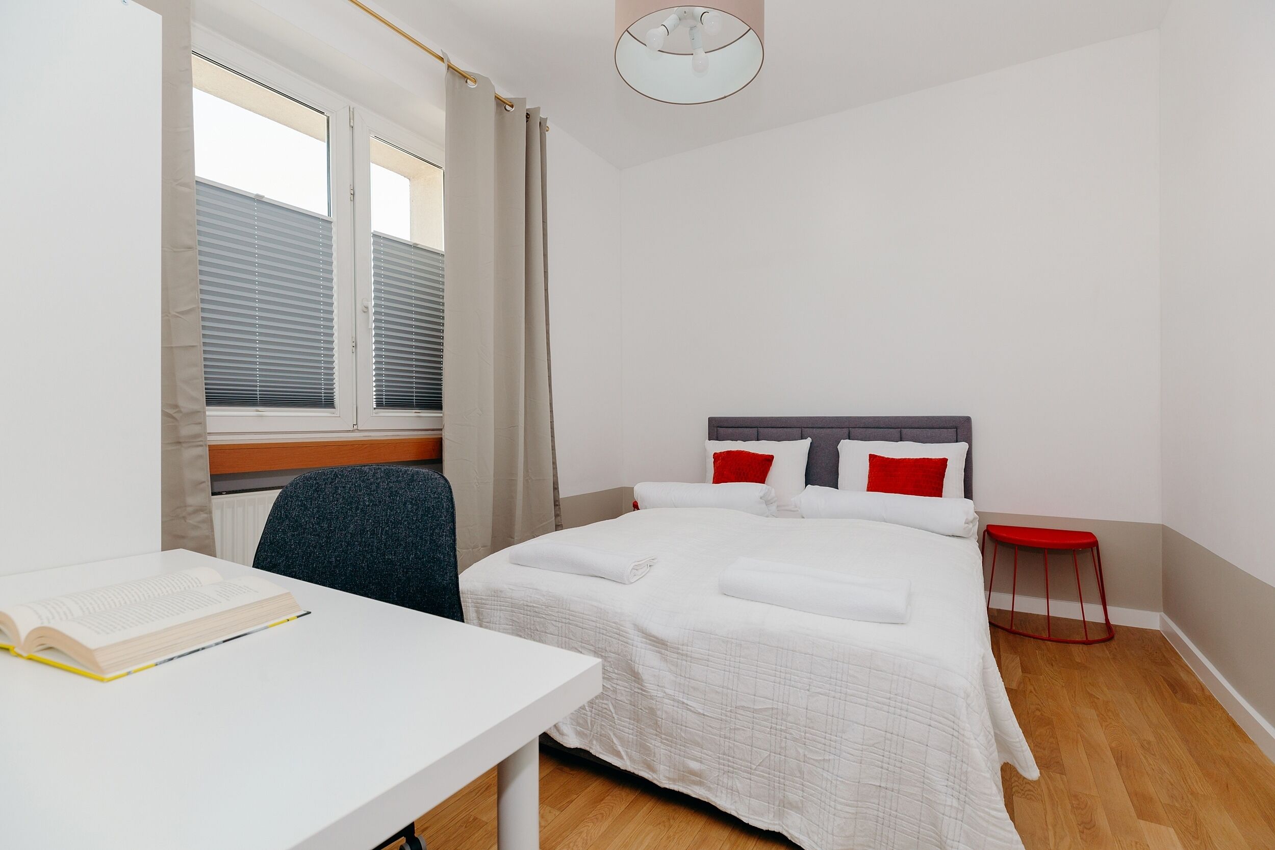 A hotel room with a bed, a desk, and a chair.