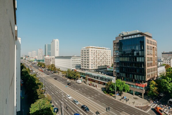 A multi-story building with a modern glass facade, adjacent to a wide urban street with vehicles and pedestrians.