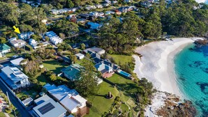 An aerial view of a coastal residential area with houses, a beach, and clear blue waters. - The Green Whaler, Hyams Beach (Hyams Beach)