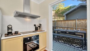 A kitchen with a built-in oven, a coffee maker, and a knife block. - The Green Whaler, Hyams Beach (Hyams Beach)