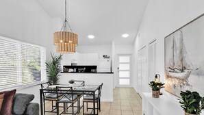 A modern kitchen with white cabinets, a dining area with a glass table, and a pendant light. - 280D - Boca Retreat w/ Pool, Parking, Near Evert Tennis & Shops (Boca Raton)