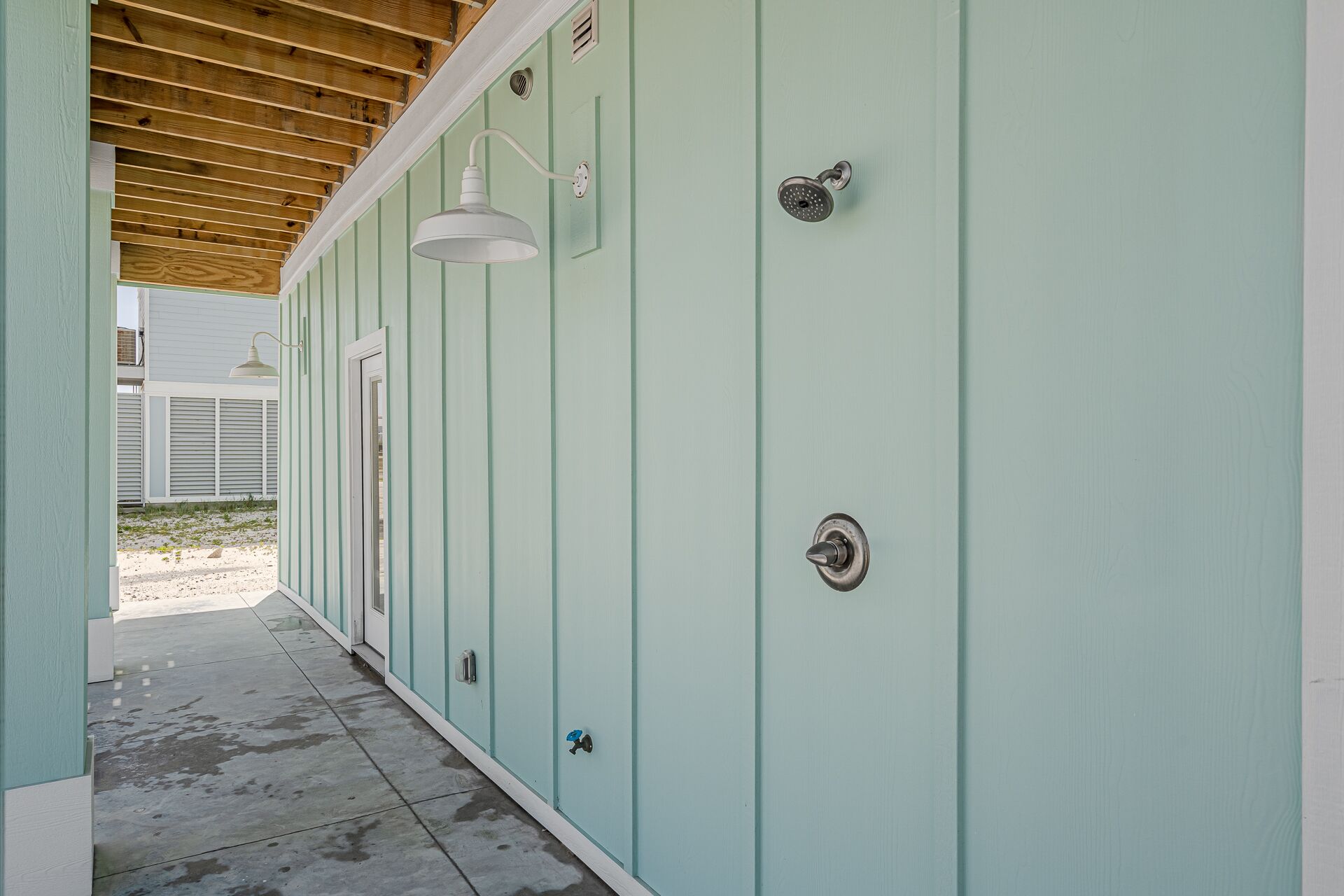 Un corridoio con pareti color acquamarina, soffitto in legno e pavimento in cemento.