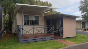 Ein kleines, eingeschossiges Mobilheim mit Veranda und überdachter Terrasse.