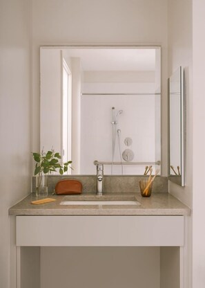 A bathroom with a large mirror, a sink, and a shower.