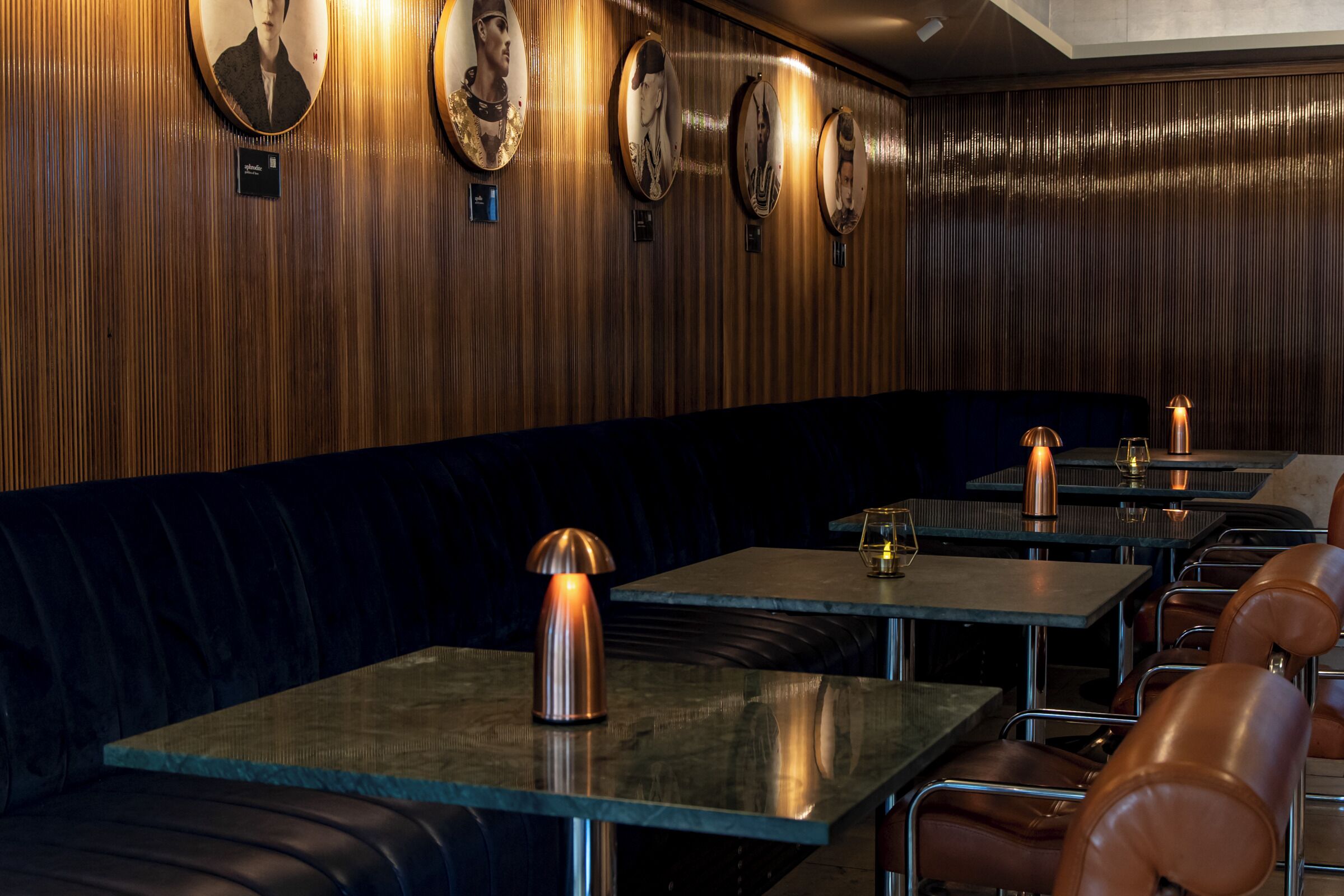 A restaurant with wooden paneling, round tables, and cushioned booths.