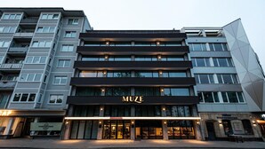 A multi-story building with a prominent 'MUZE' sign on the ground floor, featuring large windows and a modern architectural design. - MUZE Hotel Düsseldorf - Handwritten Collection (Düsseldorf)