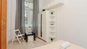 Un dormitorio moderno con cama, escritorio, silla, armario y ventana con cortinas.