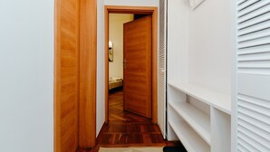 Un pasillo estrecho con puertas de madera, una pared blanca y un techo blanco.