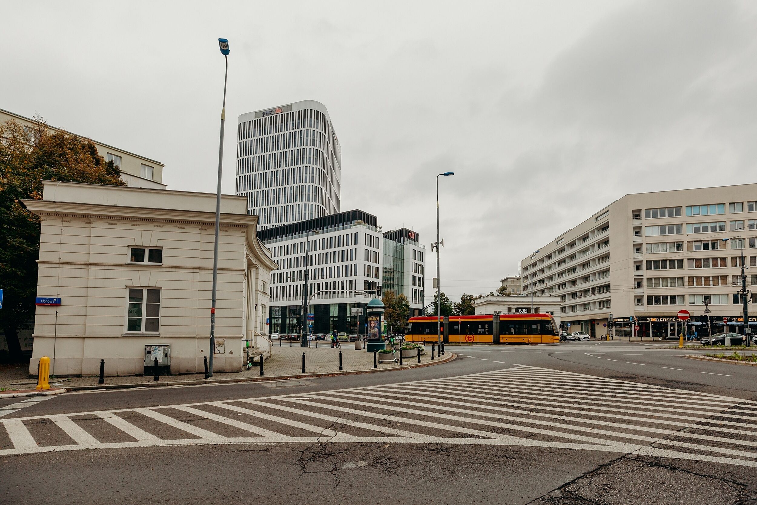 Una intersección urbana con edificios modernos, un tranvía y un paso de peatones.