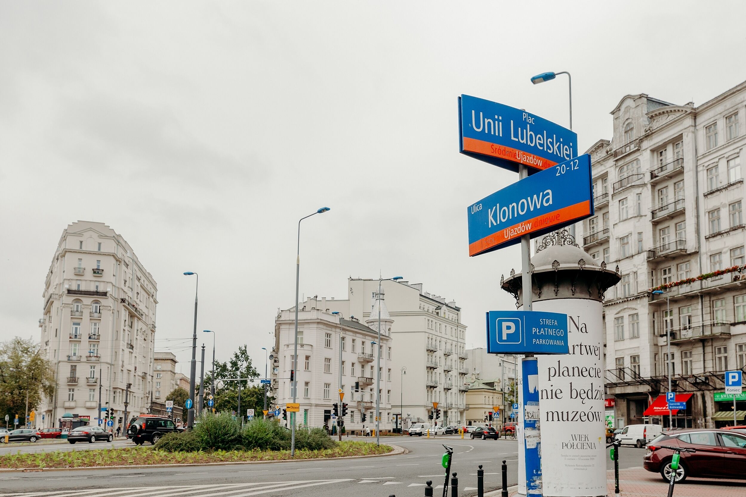 A street view with a roundabout, traffic lights, and buildings.